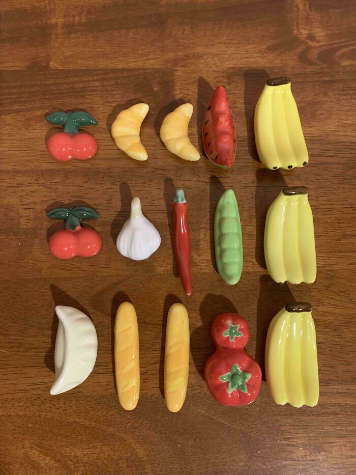 Collection of ceramic fruit and vegetable figurines arranged on a wooden surface, showcasing unique and colorful obsessions.