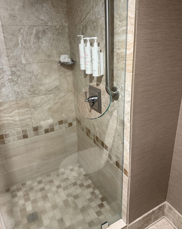 Shower with a glass cutout for easy access to faucet handle, a smart idea solving an annoying bathroom problem.