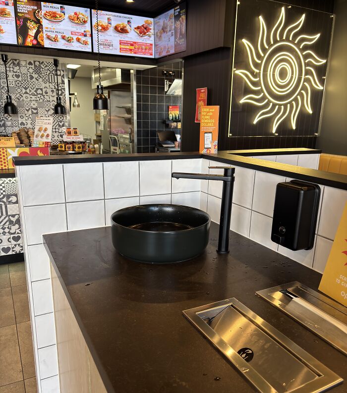 Modern restaurant handwashing station with a round black sink and touchless soap dispenser, showcasing genius problem-solving ideas.