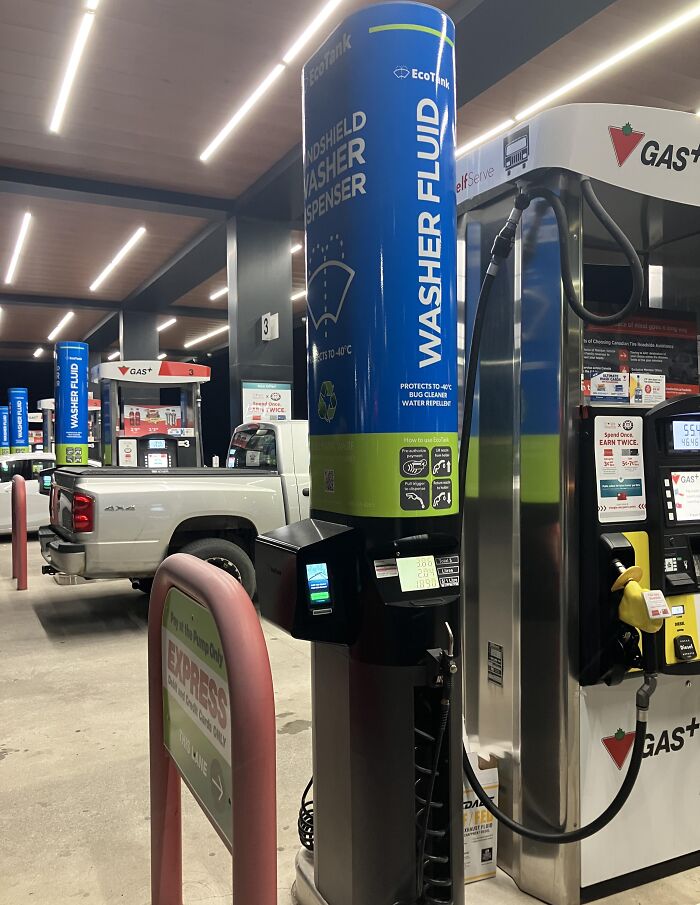 Gas station installation of washer fluid dispenser next to fuel pumps offering a convenient genius solution to car maintenance.