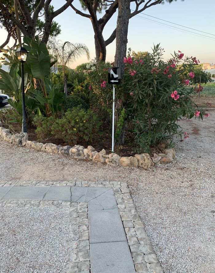 Signpost with a shoe icon cleverly uses an arrow to solve an annoying problem in garden navigation.