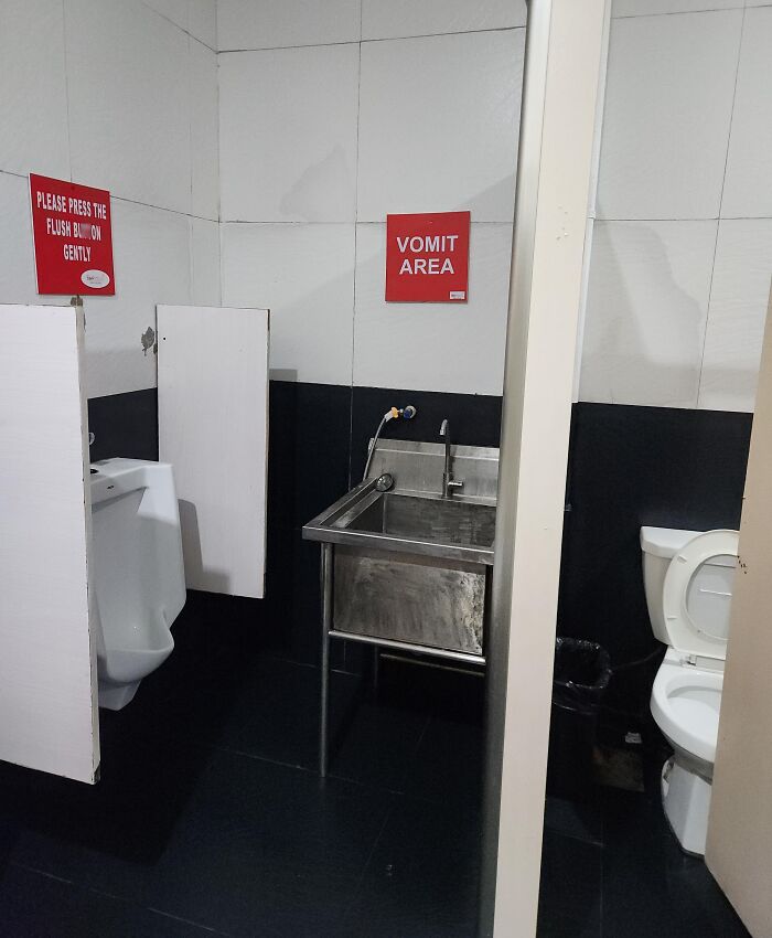 Public restroom setup with a urinal, sink labeled vomit area, and toilet showing clever problem-solving idea.