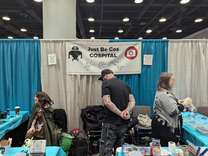 People showcasing genius ideas at a convention booth labeled Just Be Cos Cospital for solving annoying problems.