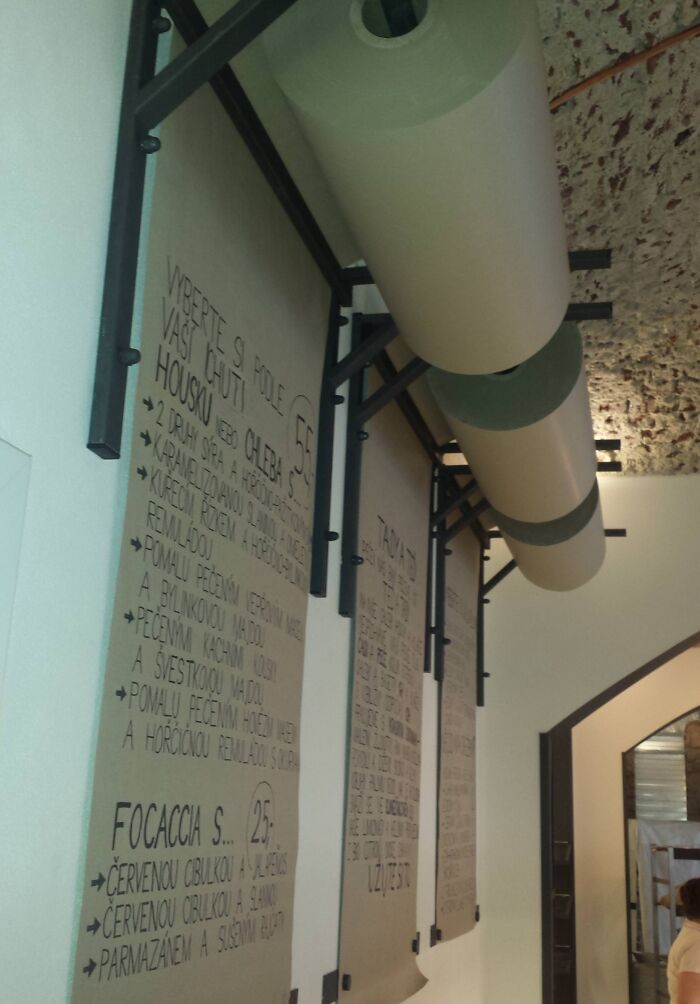 Industrial-style ceiling pipes creatively incorporated above handwritten wall menus show genius problem-solving ideas.