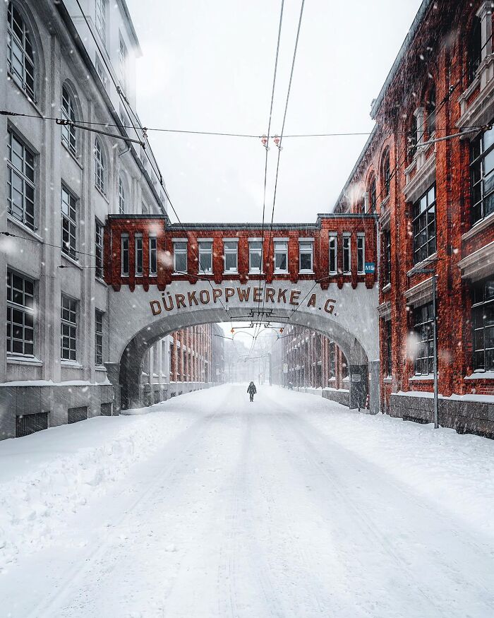 A snowy street with beautiful architecture, including a building with DÜRKOPPWERKE A.G. written on it.
