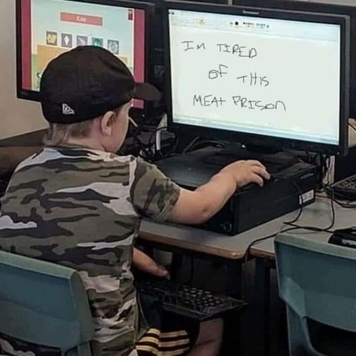 Young boy in camo shirt at computer with screen saying tired of this meat prison, a weird and cringey photo.