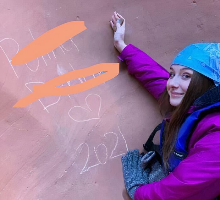 Young female influencer in purple jacket and blue bandana posing by graffiti on wall, acting like rules don’t apply to her.