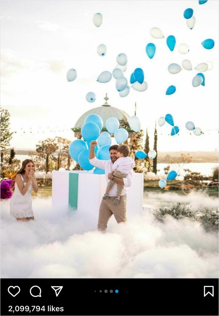 A man holding a child and a woman surrounded by balloons and fog in an outdoor setting with a festive atmosphere.