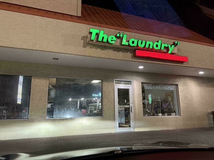 Sign for a laundromat with suspicious quotation marks around Laundry, making it look hilariously odd at night.