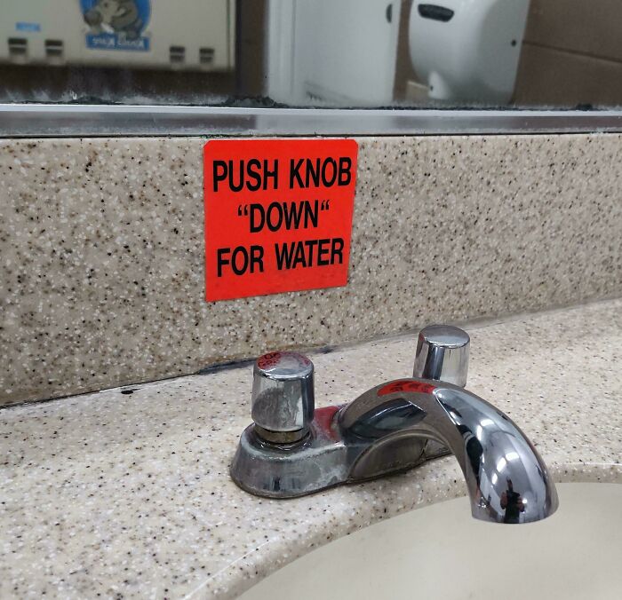 A bathroom faucet with a red sign that puts quotation marks around the word down, making it suspicious.