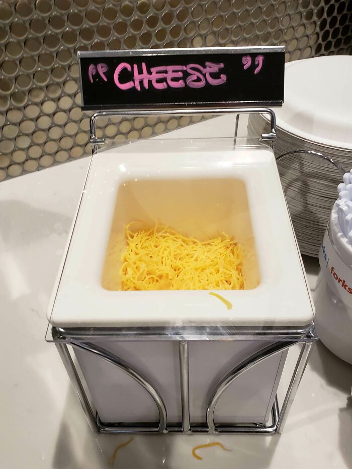 Container of shredded cheese with suspicious quotation marks around the word cheese on the label, creating a funny sign.