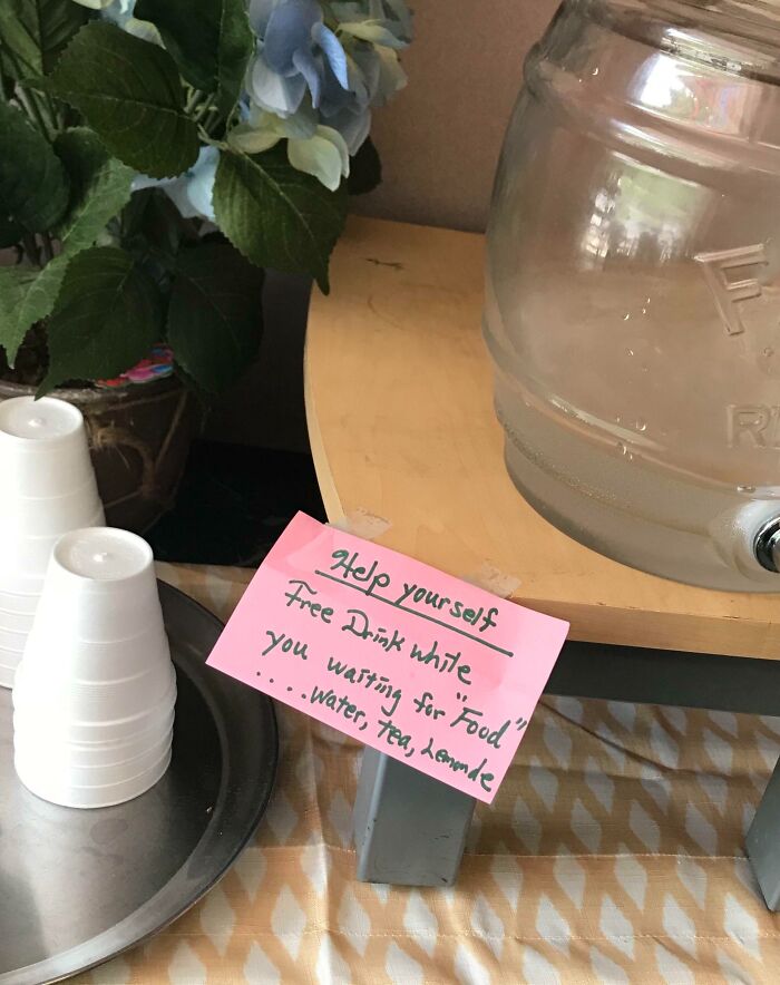Handwritten sign with suspicious quotation marks offering free drink while waiting for "food" including water, tea, lemonade.