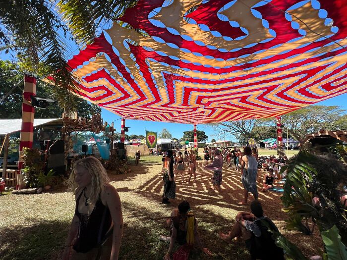 Outdoor gathering with colorful DIY fabric canopy providing shade to people enjoying a sunny communal space.