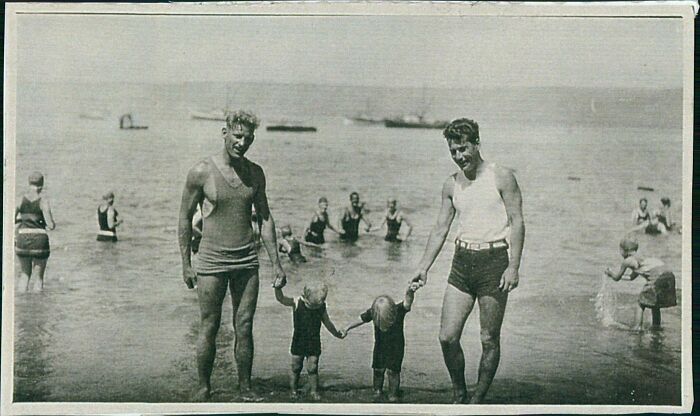 Black and white vintage photo of a family at the beach, capturing moments from decades ago with children and adults in swimwear.