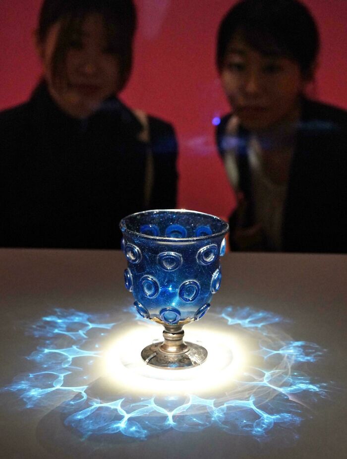 Intricate blue glass goblet displayed under light, featured among historical finds.