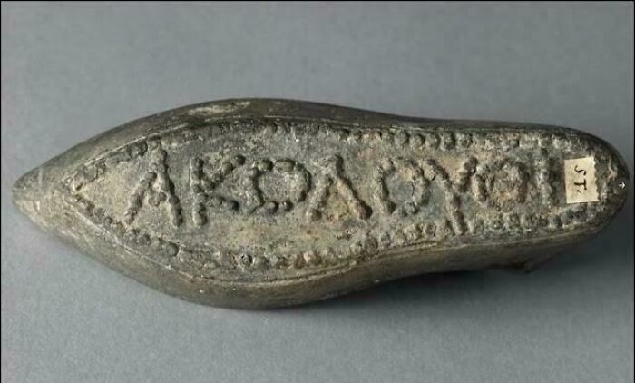 An ancient lead shoe sole stamped with Greek lettering, showcased among unique historical finds.