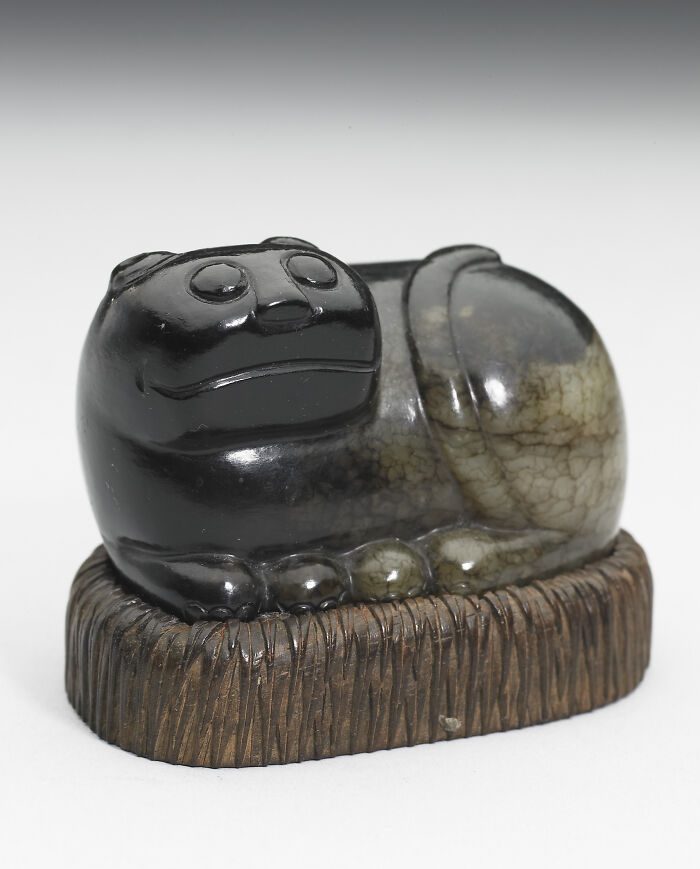 A black jade sculpture resting on a wooden base, representing unique historical finds.