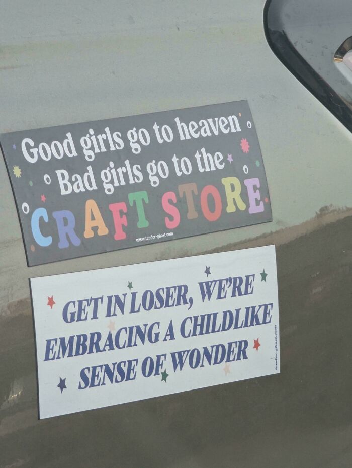 Two wild bumper stickers on a car; one about good girls and craft store, the other about childlike wonder.
