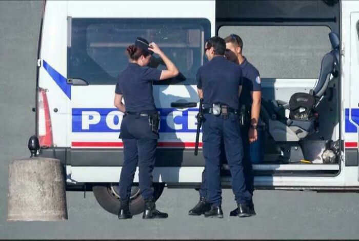 Three police officers standing by a police van, creating a misleading photo that seems like a glitch in real life