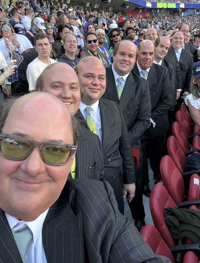 A large group of men in striped suits and light green ties, all resembling each other, in a stadium, peculiar things.