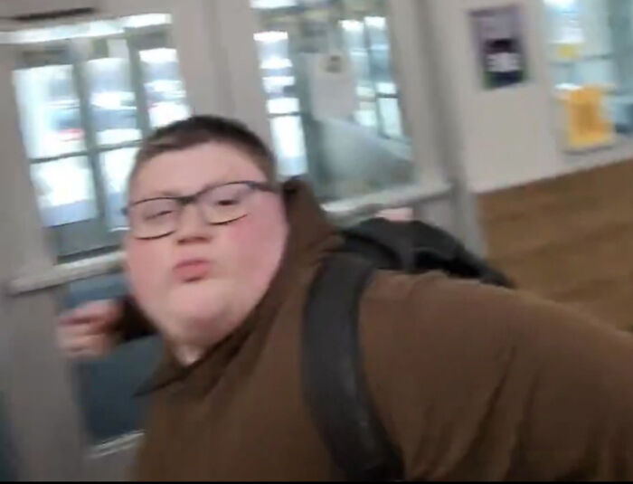 A man with glasses and a brown hoodie, making a funny face, walking through a doorway, peculiar things.