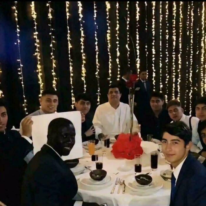 A peculiar photo of a diverse group of people posing for a picture at a table, enjoying a night out.