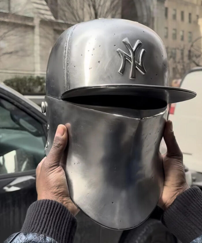 A person holds up a peculiar knight's helmet with a New York Yankees baseball cap brim, a real life spotted item.