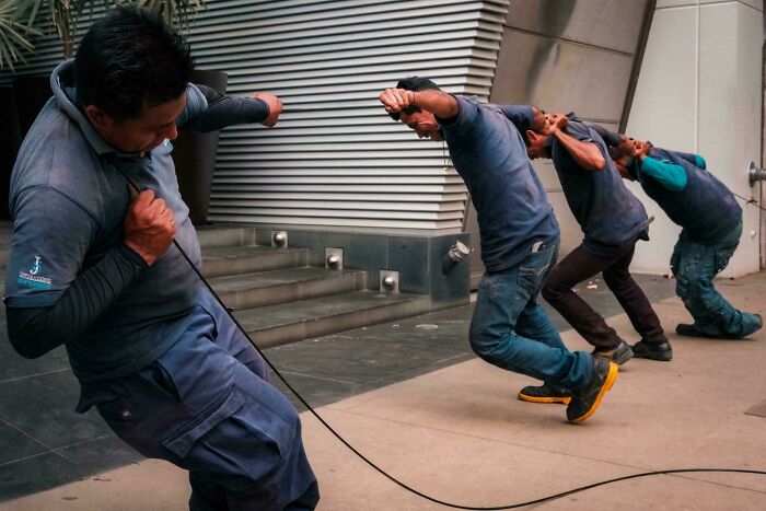 Four workers pulling a rope with effort, forming an accidental renaissance dynamic composition.
