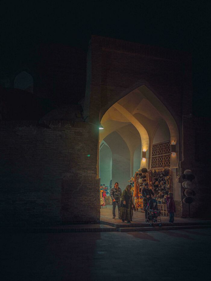 People walking through a dimly lit historical archway, showcasing accidental renaissance aesthetics.