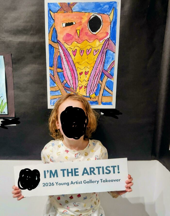 A child proudly holding an I'm The Artist sign in front of their artwork. A wholesome moment with a great dad.