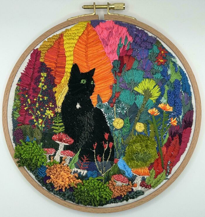 Stunning embroidery creation of a black cat surrounded by colorful plants and mushrooms, inspiring embroidery hobby.