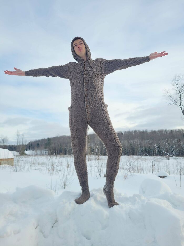 Person wearing a handmade full-body knitted suit standing outdoors in snow, showcasing a DIY wins project.