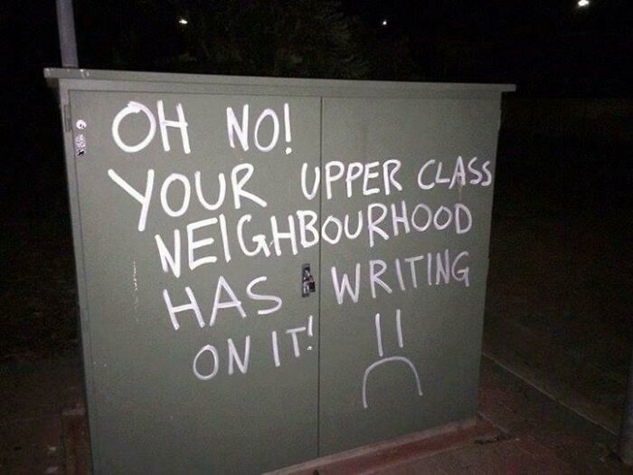 Graffiti on electrical box with humorous message, showcasing mild vandalism in an urban neighborhood at night.