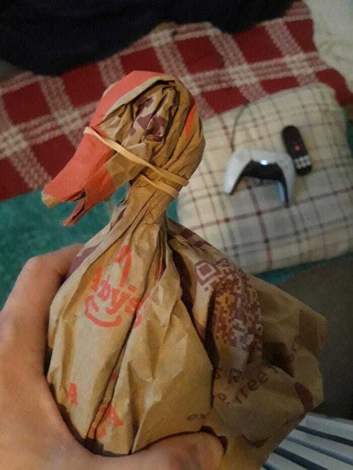 Hand holding a makeshift creepy doll made from a fast food paper bag inside an old home setting.