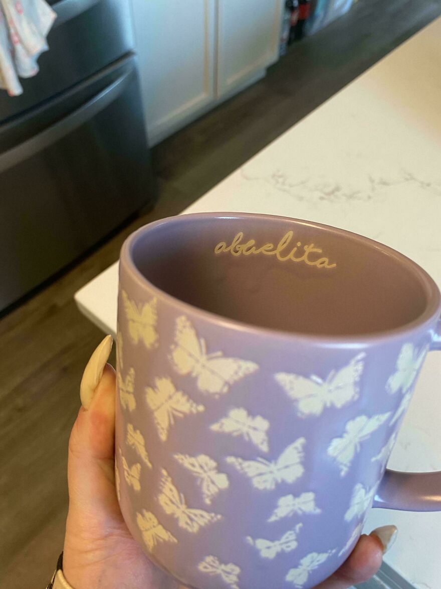 Hand holding a purple mug with white butterflies and the word abuelita inside, showing weird and unexplainable things.