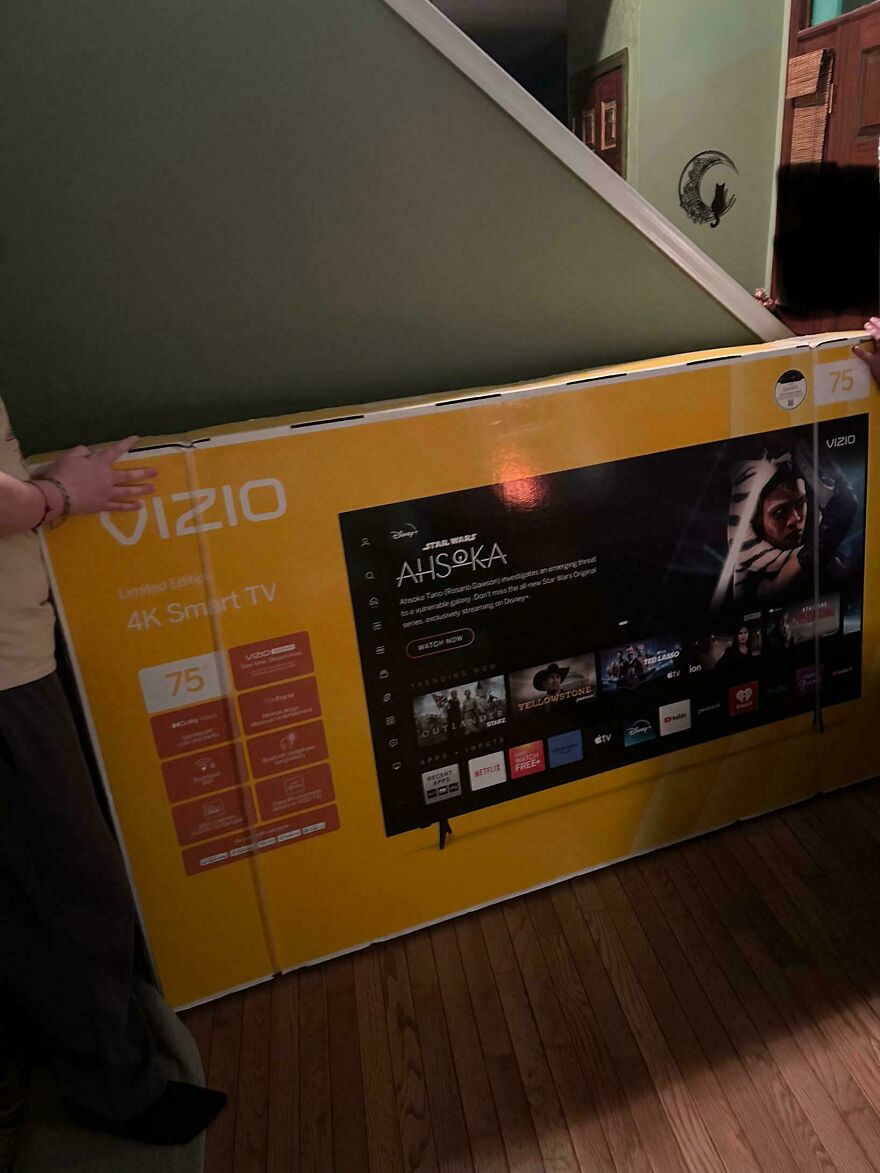 Large 75-inch Vizio 4K Smart TV box held by two people inside a home, showcasing weird and unexplainable things experienced.