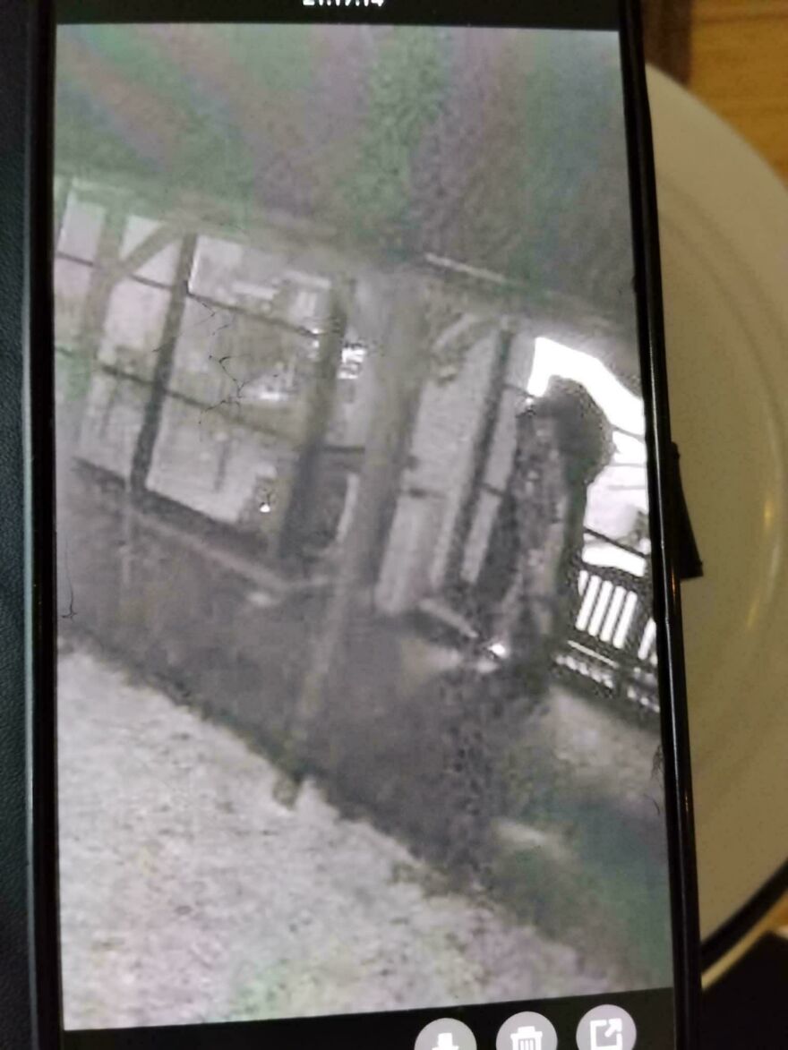 Blurry black and white image of a shadowy figure on a porch captured in weird and unexplainable things photos.