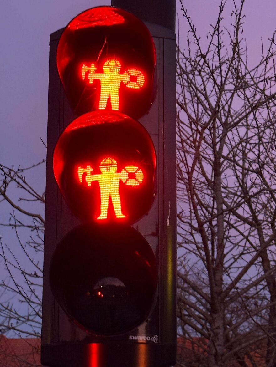 Red pedestrian traffic lights showing a person holding a hammer and a circular object, a weird and unexplainable thing experienced.