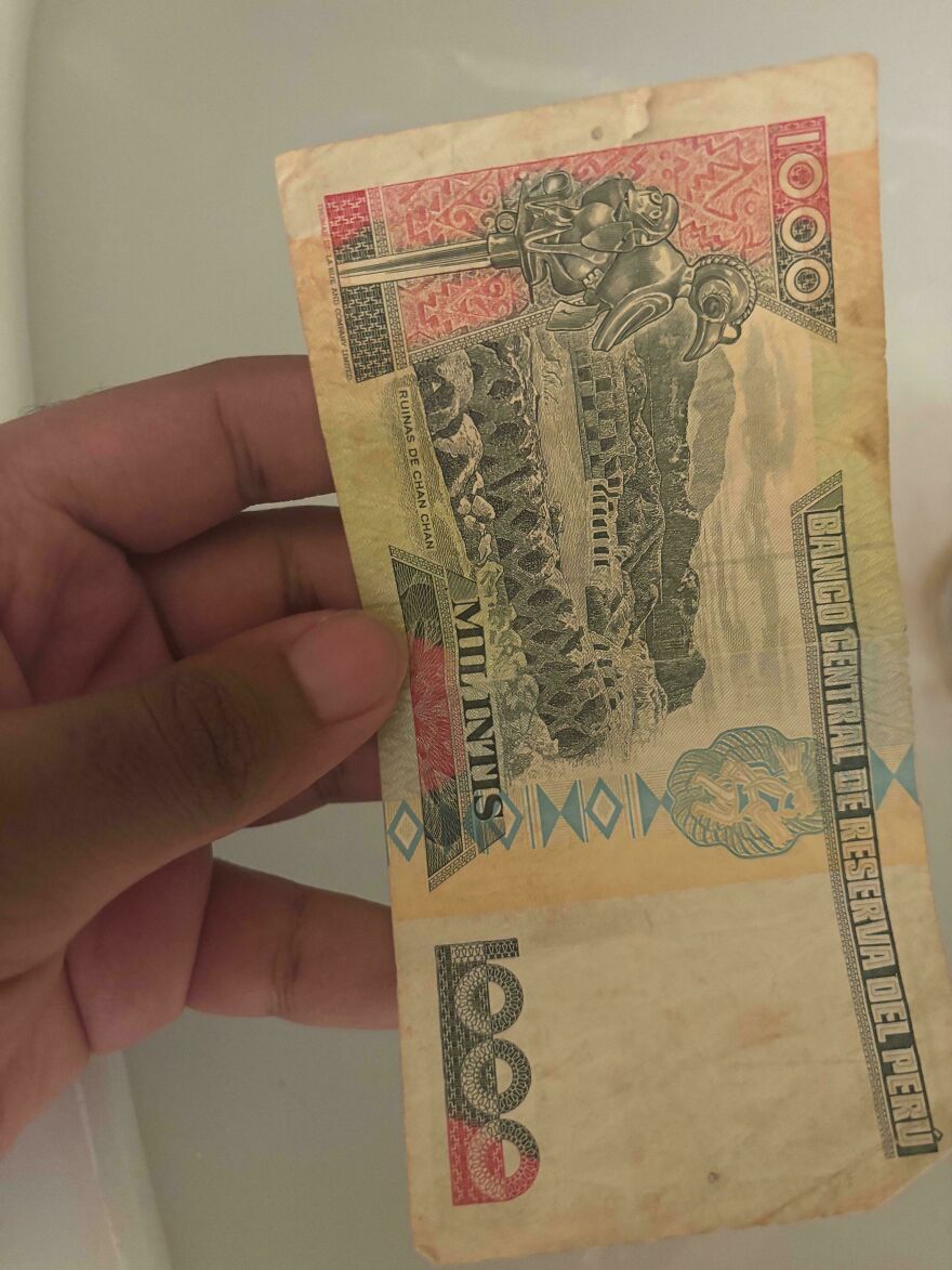 Hand holding an old, worn 1000 Peruvian banknote featuring ancient ruins and intricate designs, a weird and unexplainable sight.