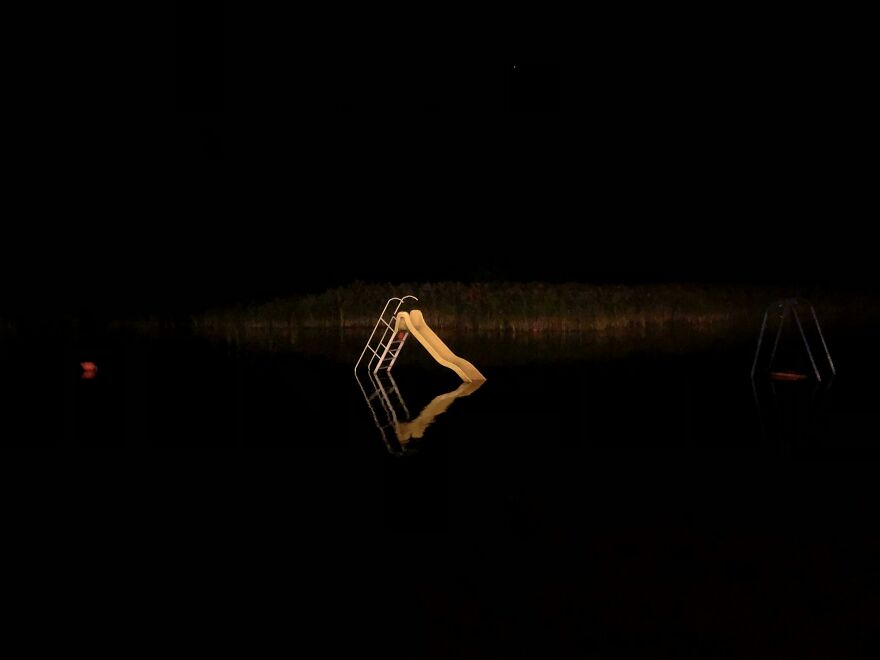 Slide partially submerged in water at night, creating a weird and unexplainable scene reflecting in the dark.