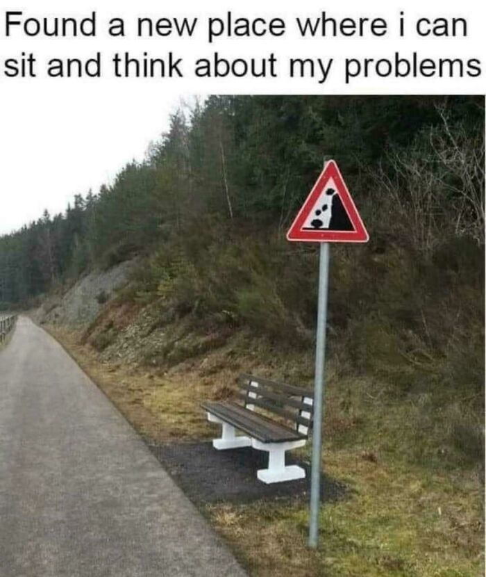Bench placed under falling rocks warning sign by a roadside, illustrating funny and relatable memes about avoiding problems.