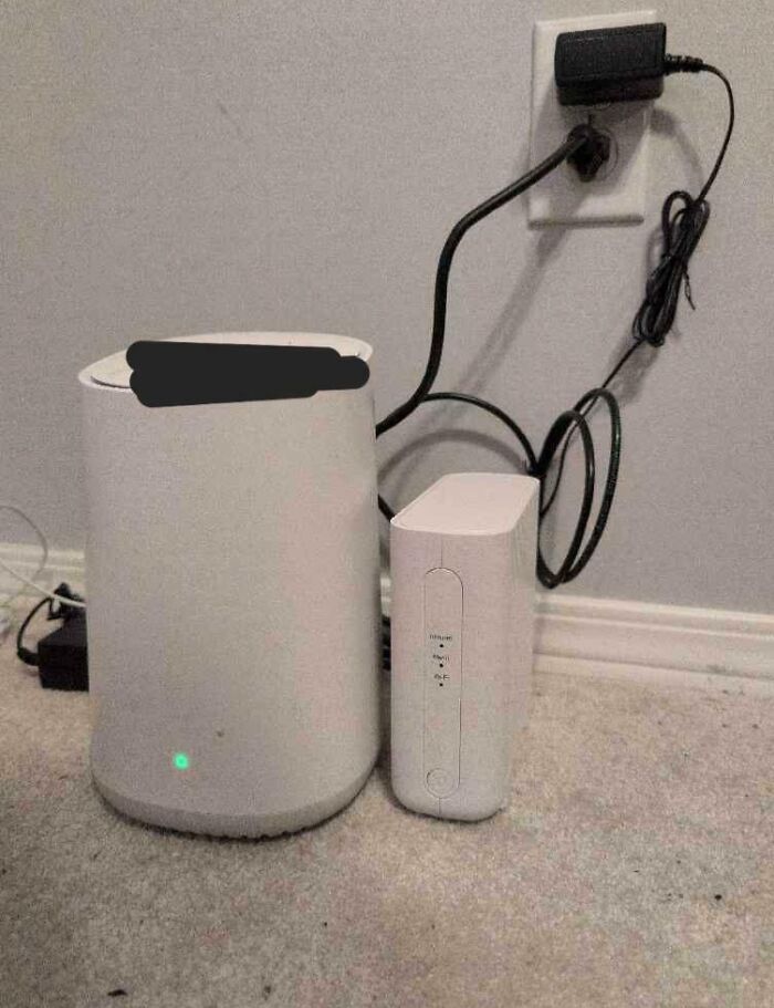 Router and modem on carpet with tangled cords plugged into a wall outlet illustrating people operating at 1% brain capacity.