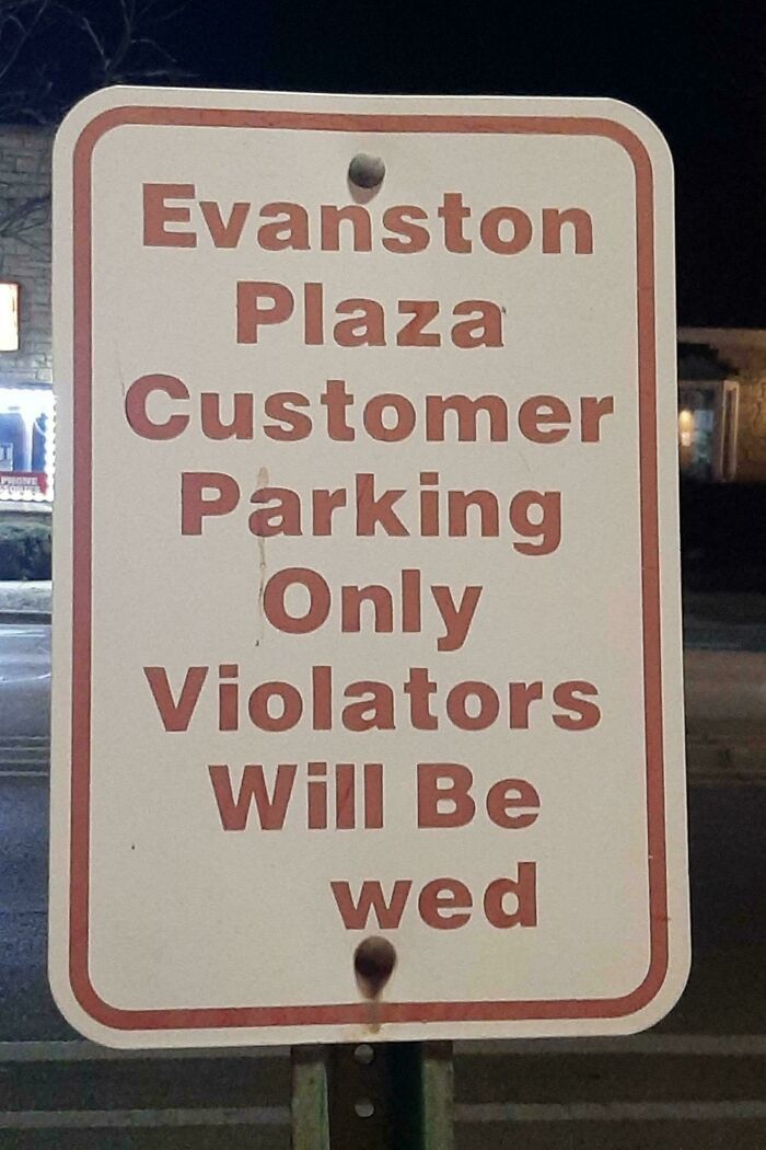 Parking sign with a humorous mild vandalism message about violators being wed in a customer parking lot at night.
