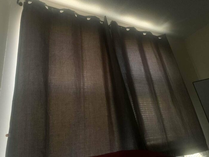 Black curtains installed incorrectly, showing a disappointing shopping fail that causes trust issues with online purchases.