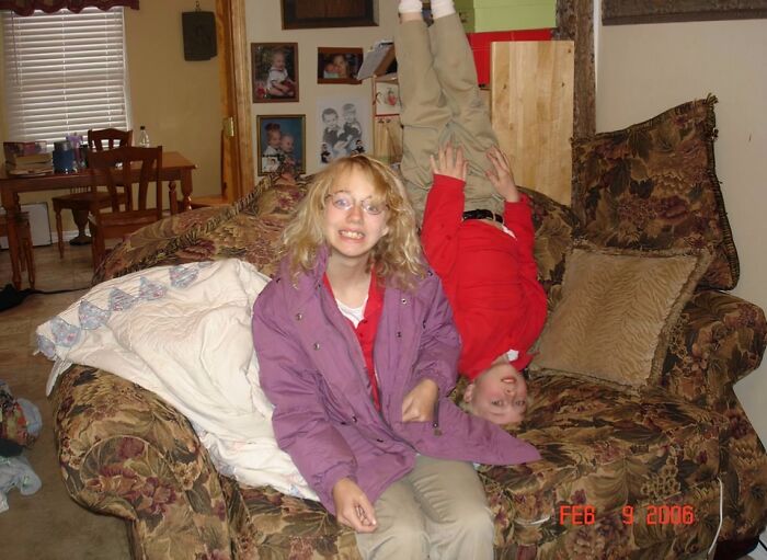 Two children pose awkwardly on a couch with one upside down, showcasing hilariously awkward childhood pics.