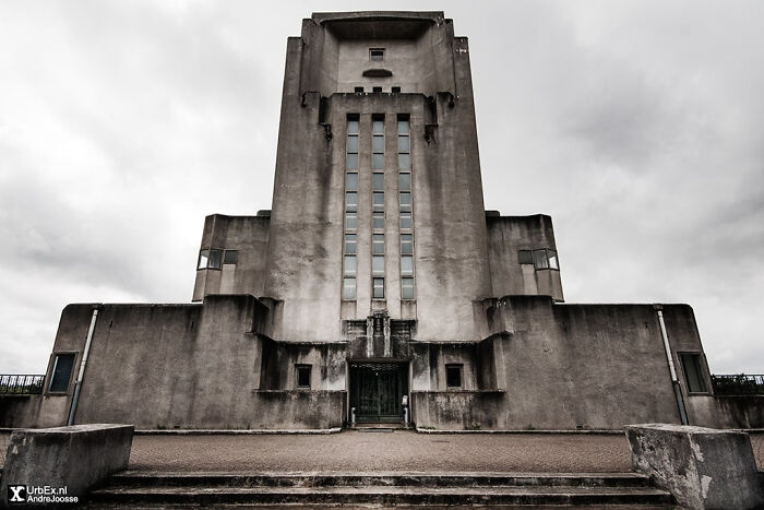 An imposing, brutalist concrete building with a central tower and narrow windows, perfect for an evil mastermind.