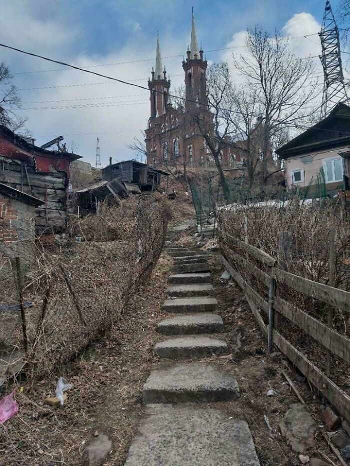 Urban hell image of rough steps leading through a rundown area towards a gothic church with tall spires