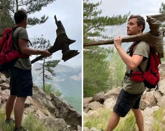 Person hiking in a forest carrying a large, cool stick shaped like a boot on a mountainous trail.