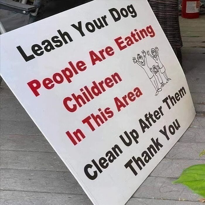 Humorous sign warning to leash dogs with people eating children text, causing double take and laughter.