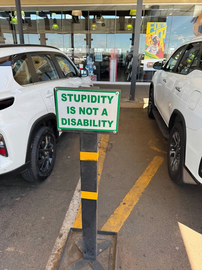 Funny sign in a parking lot stating stupidity is not a disability, causing people to laugh or do a double take.